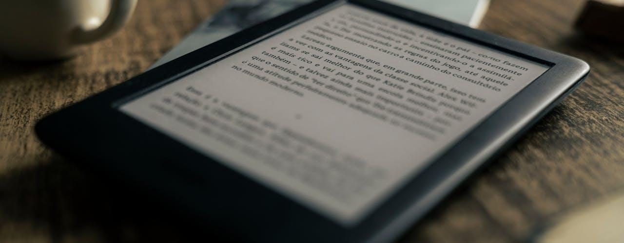 gros plan sur une liseuse présentant un texte en espagnol, posée sur une table en bois