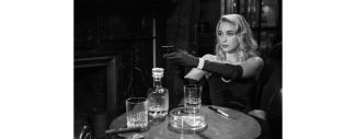 photo de femme en noir et blanc assise et visant avec un pistolet extrait d'un film