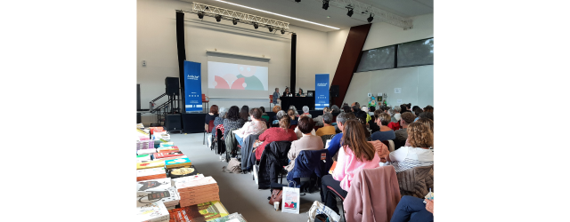 photo d'une assemblée de dos avec des livres jeunesse exposés à droite